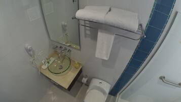 A bathroom with a glass sink, a toilet, a shower, and a towel rack.