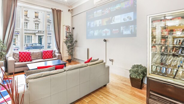 Una sala de estar moderna con un sofá, una mesa de centro y una pantalla de proyección mostrando una película.