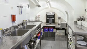 Una cocina comercial con electrodomésticos de acero inoxidable, un lavamanos doble y estantes de almacenamiento.