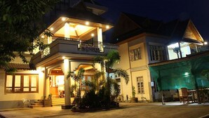 A multi-story hotel with a prominent entrance, balconies, and a well-lit facade. - Mr. Charles Hotel (Hsipaw)
