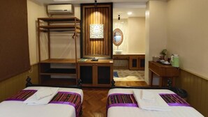 A hotel room with two beds, a desk, a mirror, and a wardrobe. - Mr. Charles Hotel (Hsipaw)