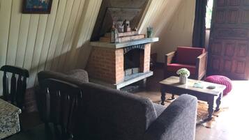A cozy room with a brick fireplace, a red chair, and a wooden table.