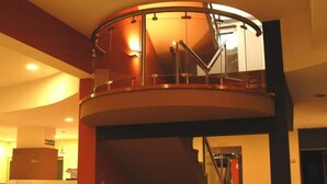 A circular atrium with a glass railing and a staircase leading to an upper level. - Hotel Nuevo Mundo (San Rafael)