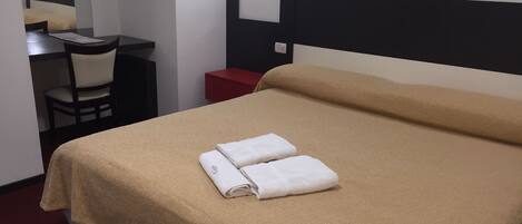 Una habitación de hotel con una cama, un escritorio, una silla y una mesita de noche roja.