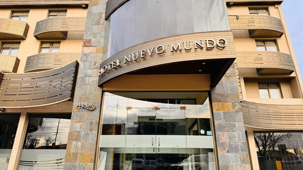 A hotel entrance with a curved facade, large glass doors, and a sign reading "HOTEL NUEVO MUNDO". - Hotel Nuevo Mundo (San Rafael)