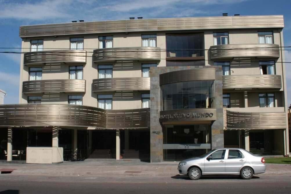 Un hotel de varios pisos con diseño moderno, que cuenta con balcones en cada planta y una entrada central.