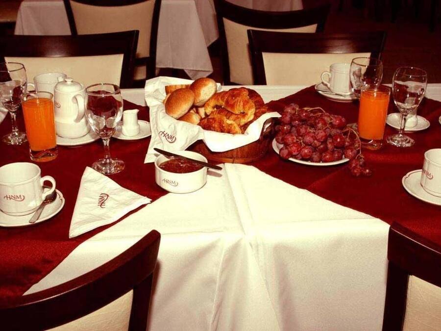 A breakfast setting with a table set for two, including croissants, grapes, and orange juice.