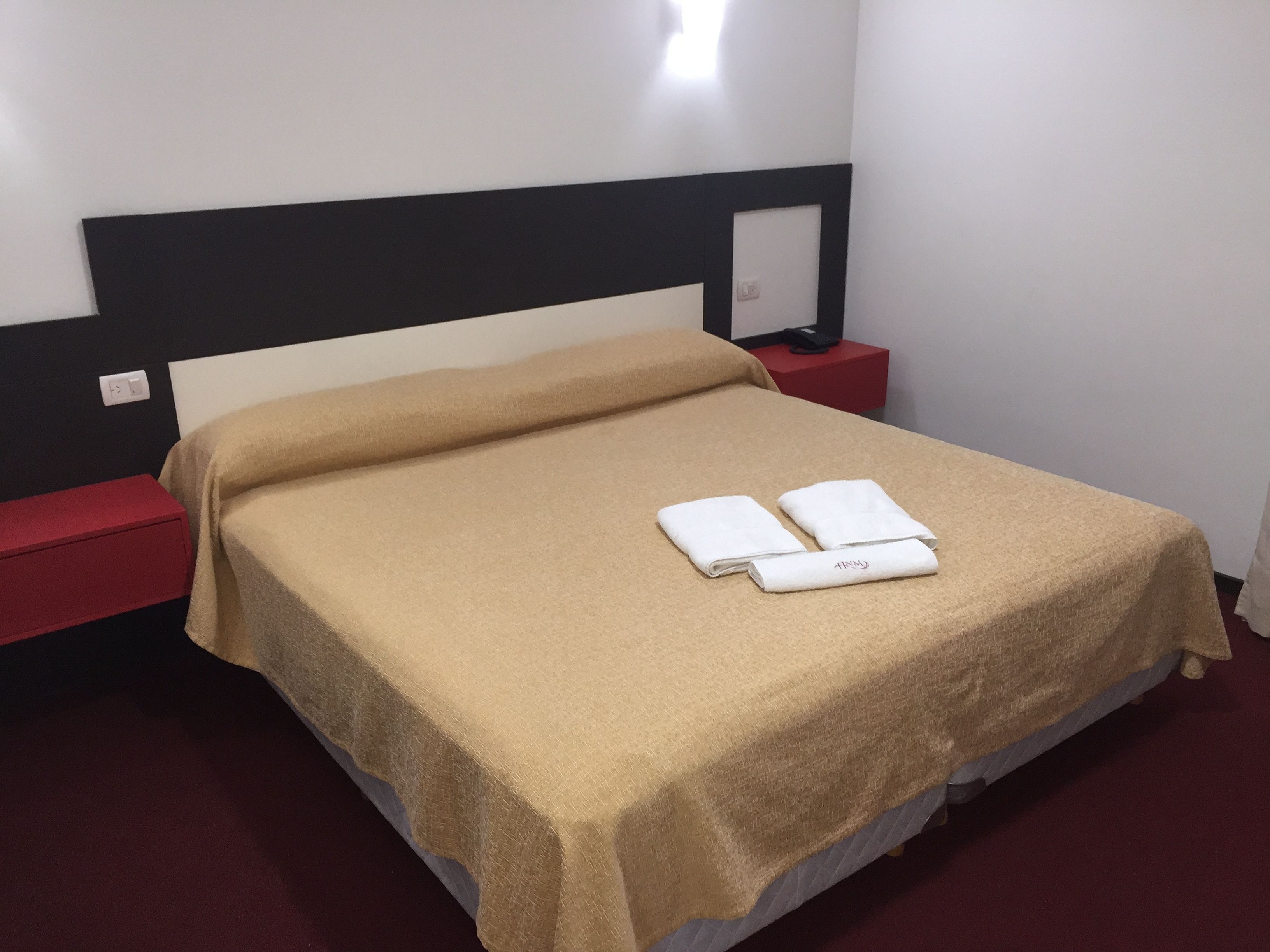 A neatly made bed with a beige bedspread and two folded white towels.