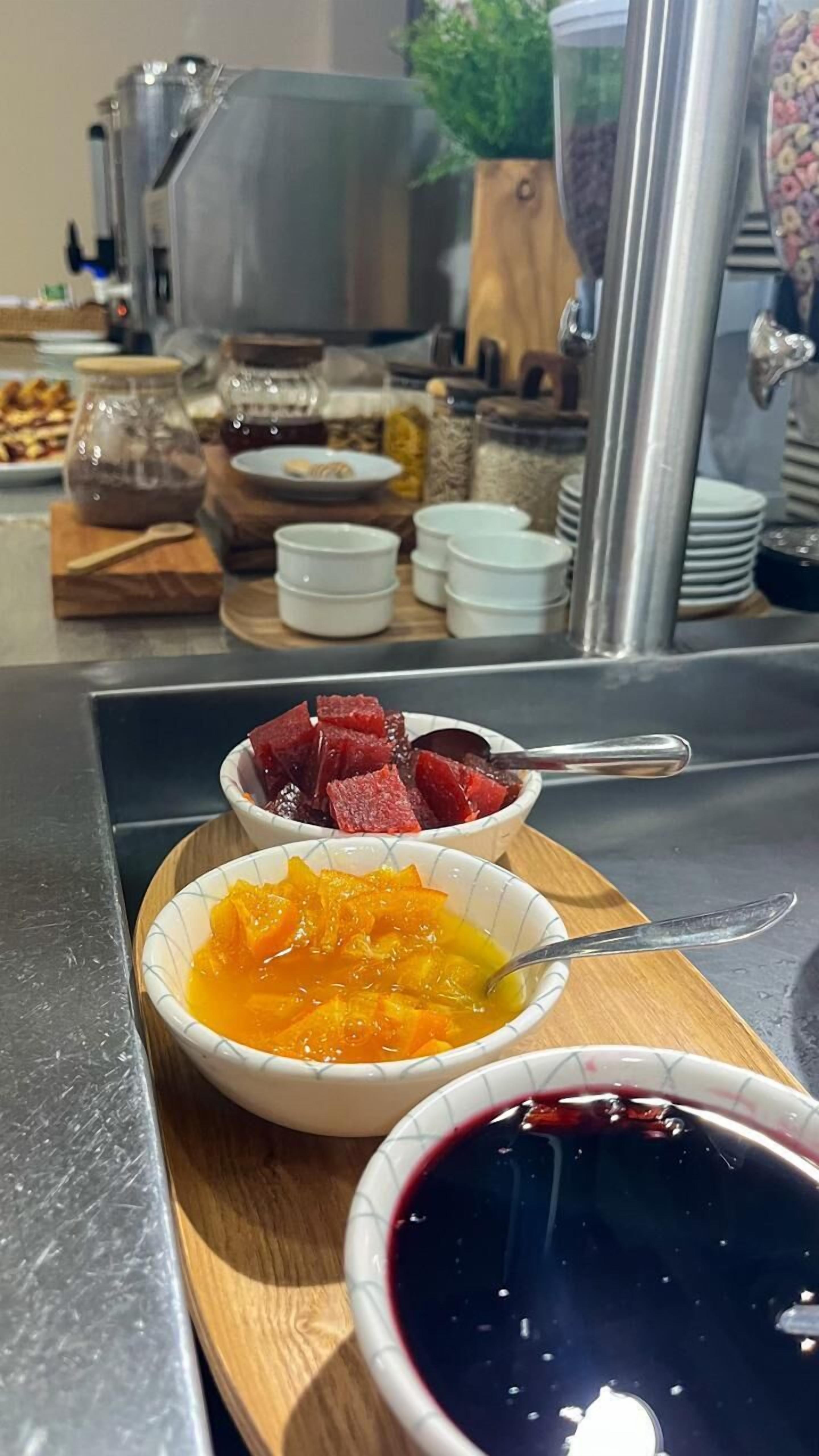 A breakfast buffet with various dishes including fruit and a dark beverage.