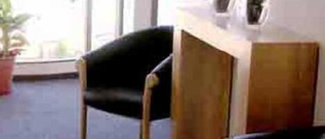 A room with a wooden desk, a black chair, and a potted plant on the desk.