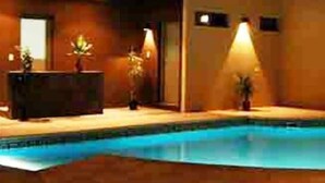 A pool area with a reception desk, potted plants, and a warm ambient light. - Hotel Nuevo Mundo (San Rafael)