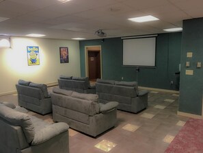 A home theater room with four gray reclining chairs, a large screen, and a projector. - Carriage House Country Club (Pocono Manor)