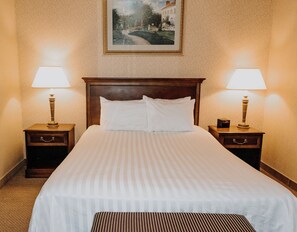 A hotel room with a large bed, two bedside tables with lamps, a framed picture on the wall, and a carpeted floor. - Carriage House Country Club (Pocono Manor)
