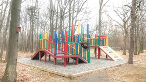 A playground with colorful play structures in a wooded park area. - Carriage House Country Club (Pocono Manor)