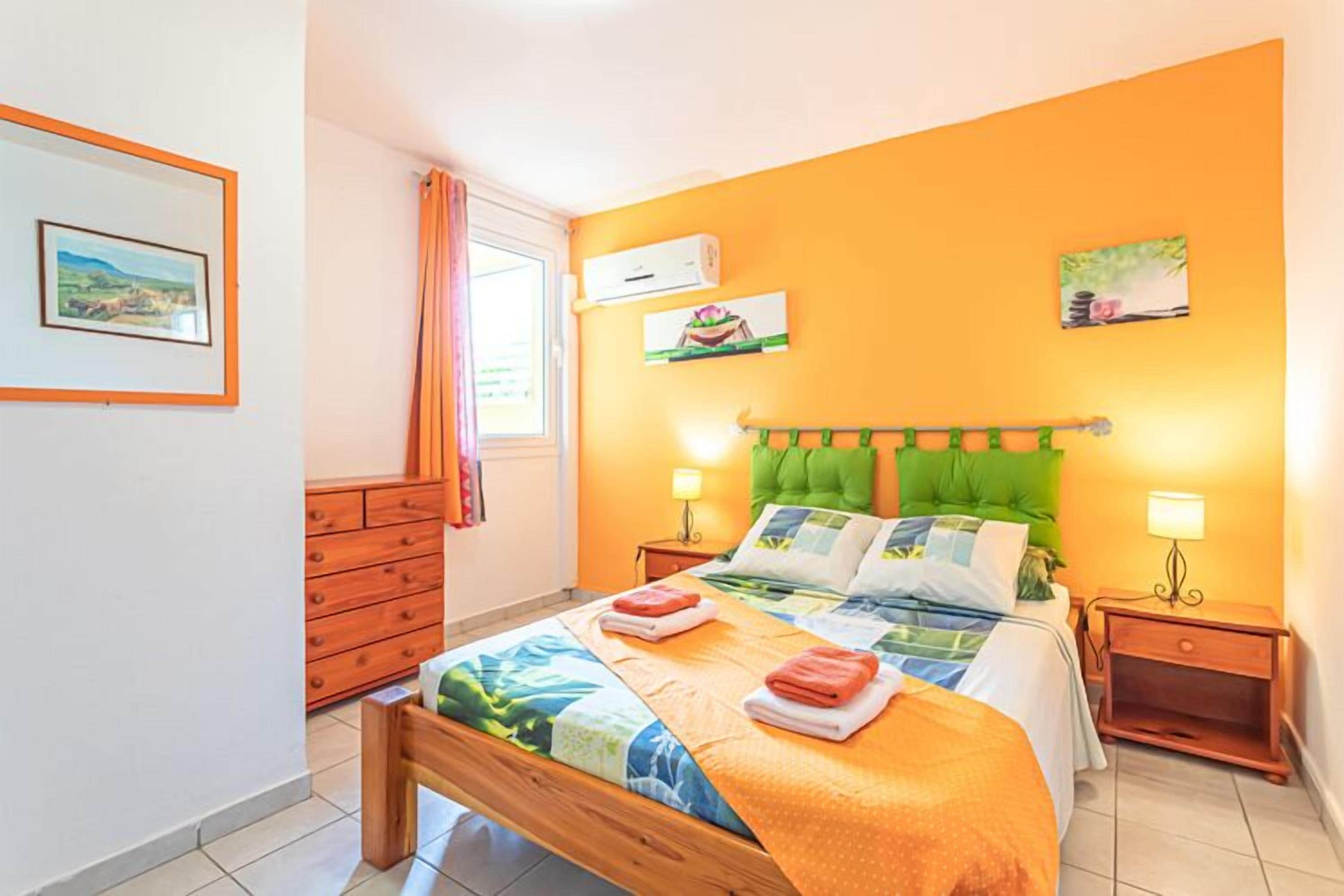 Een slaapkamer met een bed, twee nachtkastjes, een dressoir en een raam met gordijnen.