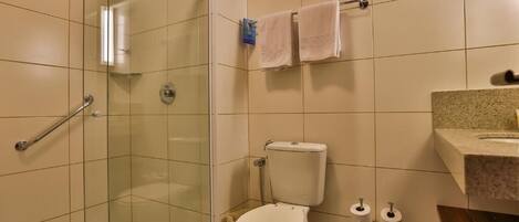 A bathroom with a glass shower enclosure, a toilet, and a sink with a granite countertop.