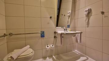 Un baño con inodoro, secamanos y un lavabo con espejo.