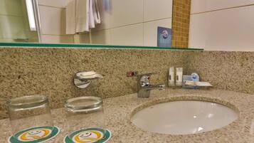 A bathroom with a granite countertop, a sink, and a mirror. There are two glass jars with smiley face stickers on the counter.