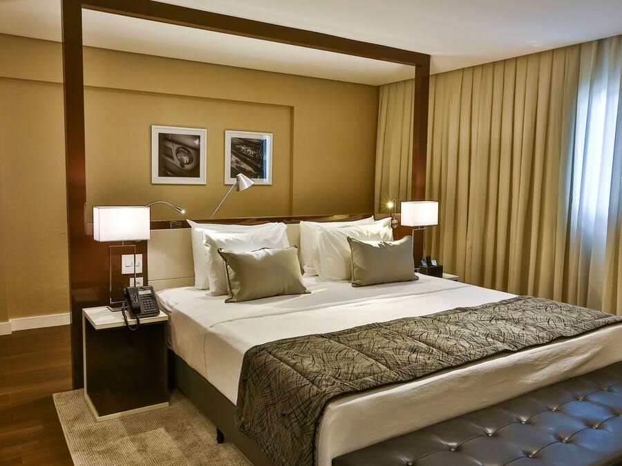 A hotel room with a large bed, two bedside tables with lamps, a telephone, and two framed pictures on the wall.
