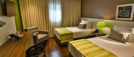 Habitación de hotel con dos camas, un escritorio, una silla, un televisor y una lámpara.