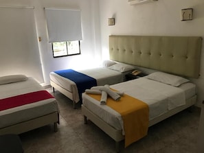 A hotel room with two single beds, a small desk, and a window with blinds. - Hotel Zenú (Montería)