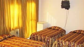 Una habitación con cuatro camas, cada una con ropa de cama estampada con motivos florales, un ventilador de techo y un televisor montado en la pared.