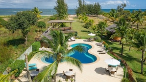 A resort with a swimming pool, lounge chairs, and a view of the ocean. - Pousada Barrabella (Maraú)
