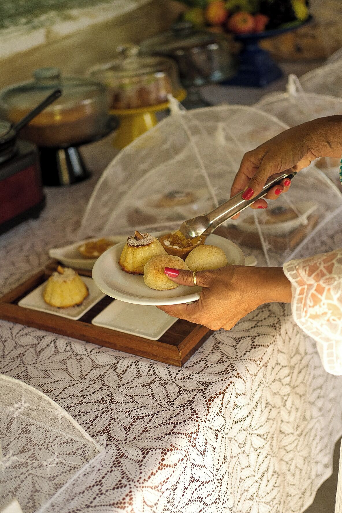 A person serving food from a covered tray onto a plate.