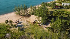 A coastal property with a beach, palm trees, and a view of the ocean. - Pousada Barrabella (Maraú)