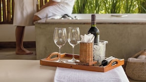 A tray with two wine glasses, a bottle of wine, a wicker basket, and a glass container with ice and a napkin on a table. - Pousada Barrabella (Maraú)