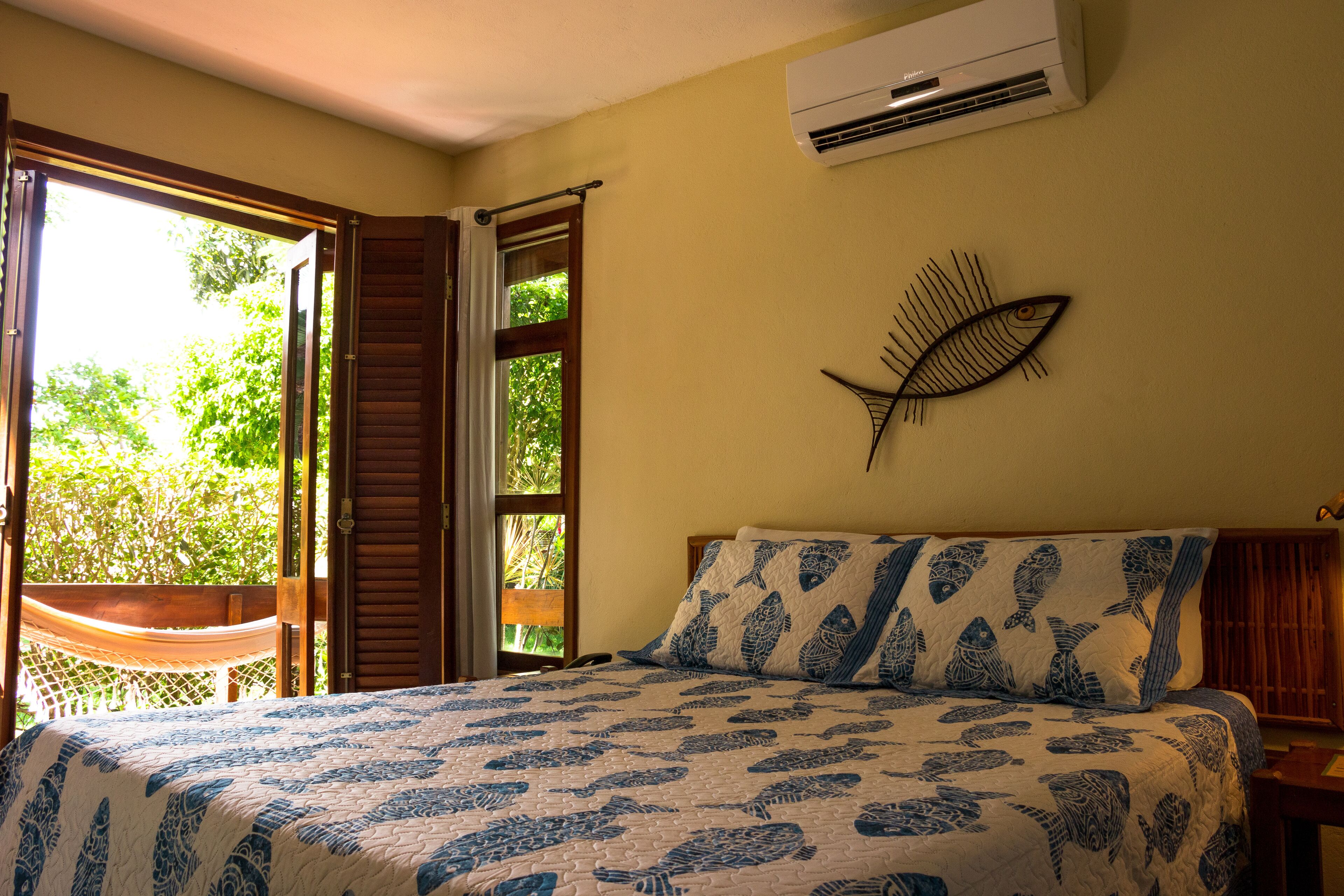 Un dormitorio con cama, hamaca y vistas al verdor exterior.