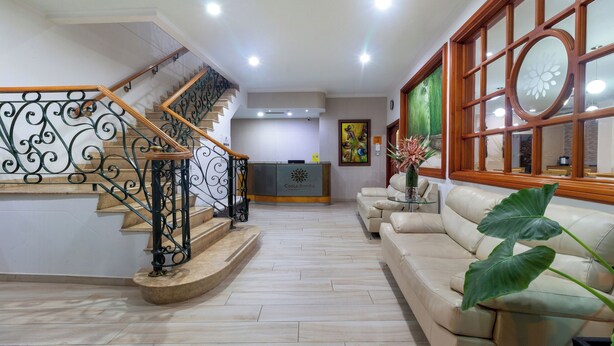 A spacious living area with a staircase, a reception desk, and a large window with a decorative frame.