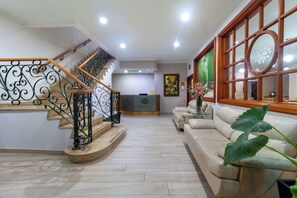 A spacious living area with a staircase, a reception desk, and a large window with a decorative frame. - Hotel Costa Bonita (Montería)