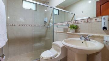 Une salle de bain avec une douche à parois de verre, des toilettes et un lavabo.