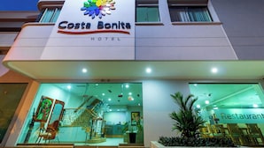 The Costa Bonita Hotel with a modern facade, a visible restaurant area, and a reception desk.