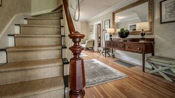 A staircase with a wooden handrail, a wooden bench, and a mirror on the wall.
