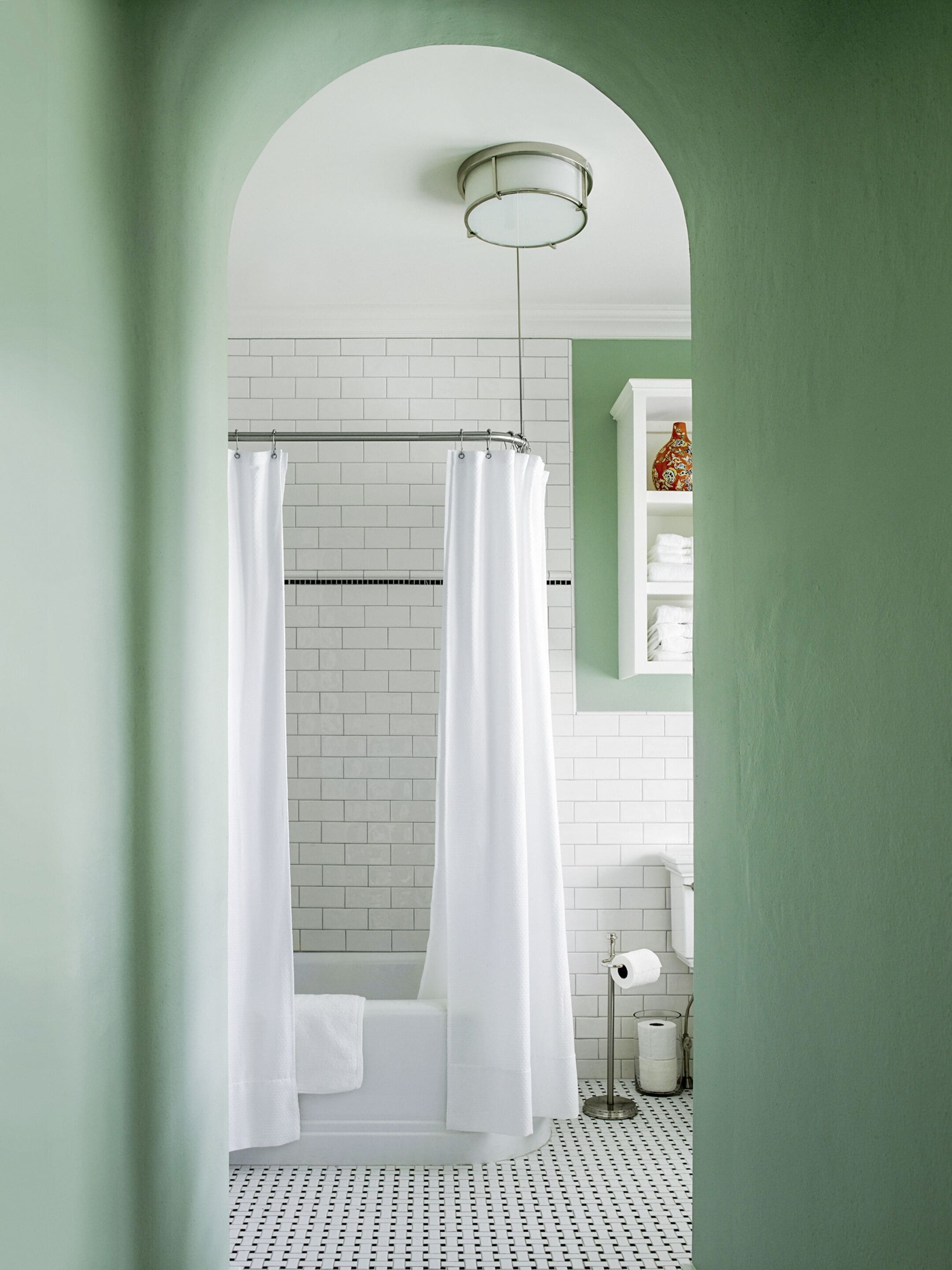 A modern bathroom with a white bathtub, a shower curtain, and a toilet.