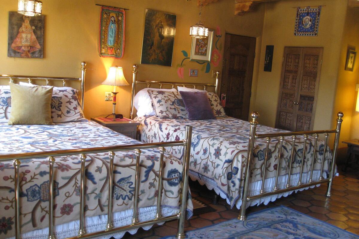 Une chambre traditionnelle avec deux lits, une table de chevet, une lampe et des éléments décoratifs fixés au mur.