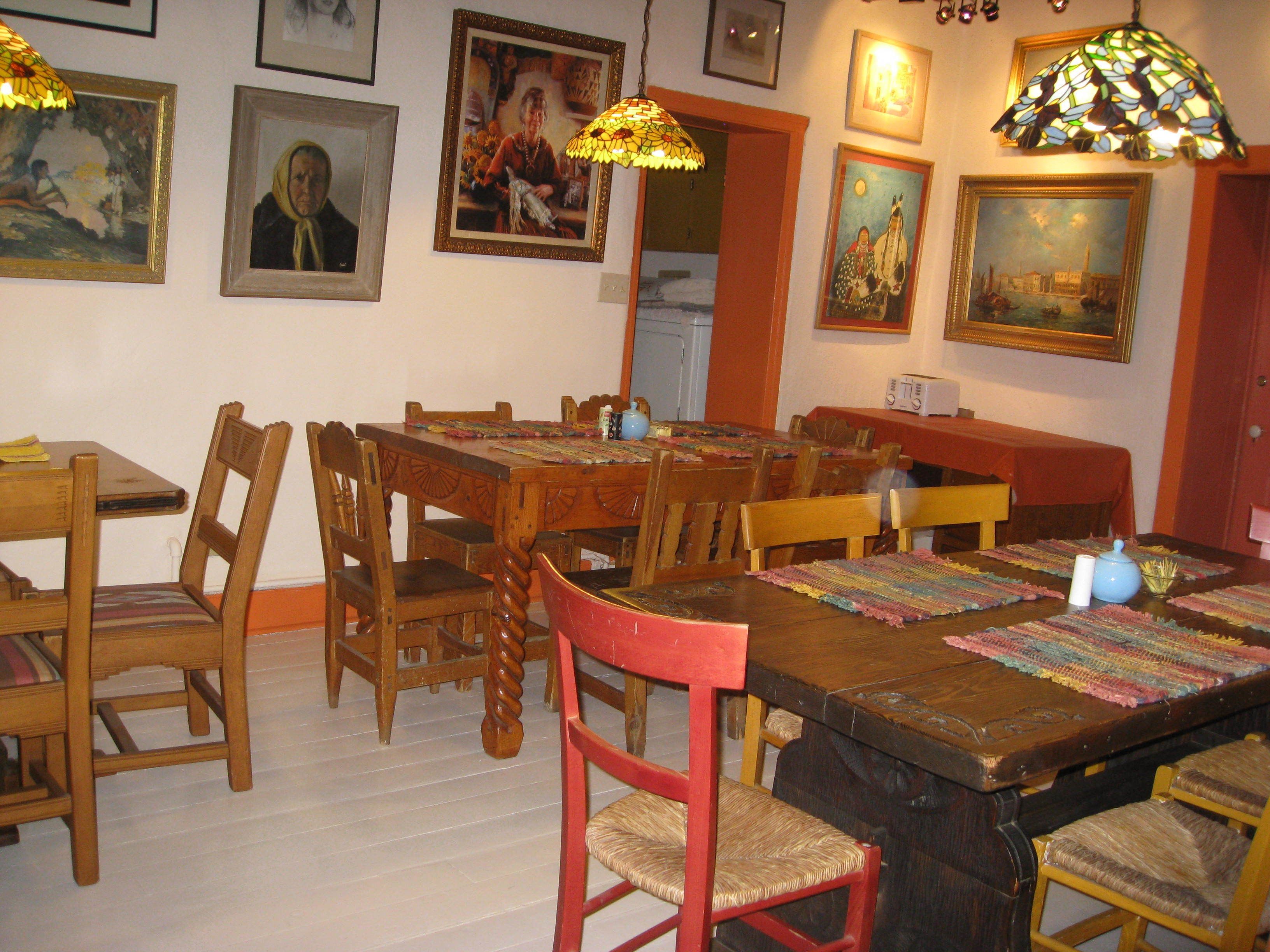Un comedor con mesas y sillas de madera, un mantel con estampado y una lámpara de vitral.