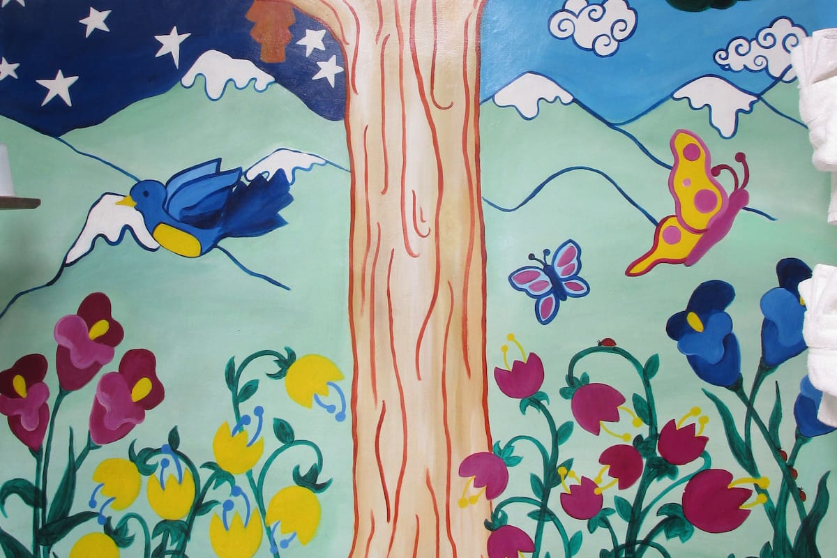 Une fresque représentant un arbre, une grenouille, des fleurs et un oiseau, peinte dans une salle de bain.