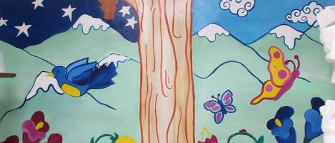 A mural of a tree with a frog, flowers, and a bird in a bathroom.