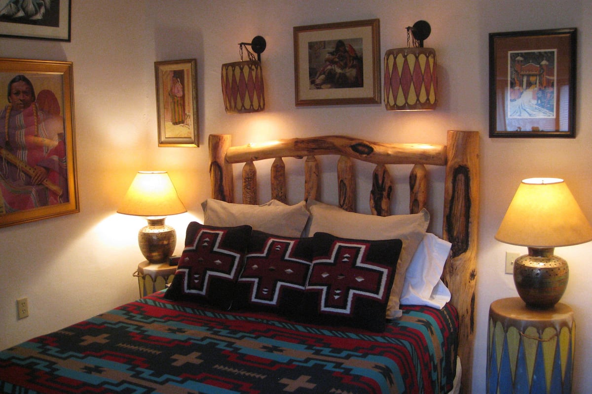 Un lit avec une tête de lit en bois, deux lampes de chevet et une couvre-lit à motifs.
