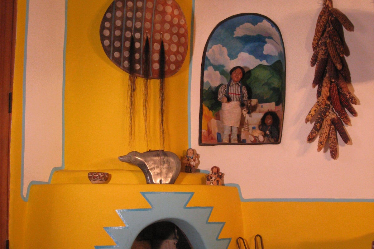 Une pièce avec une cheminée, un mur orné d’un motif circulaire et un tableau.