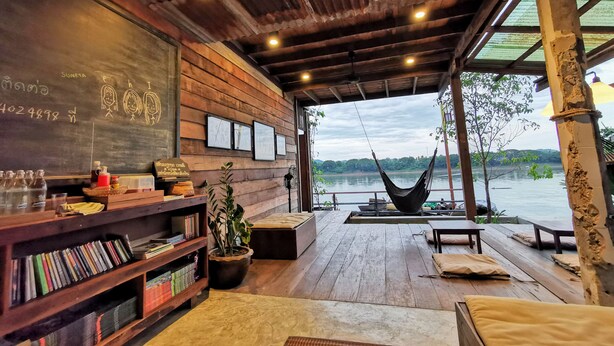 Un interno in legno con un'amaca, scaffali e vista su un lago.