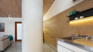Eine moderne Küche mit einer zentralen Säule, einer integrierten Spüle und einer Wand mit Holzvertäfelung.