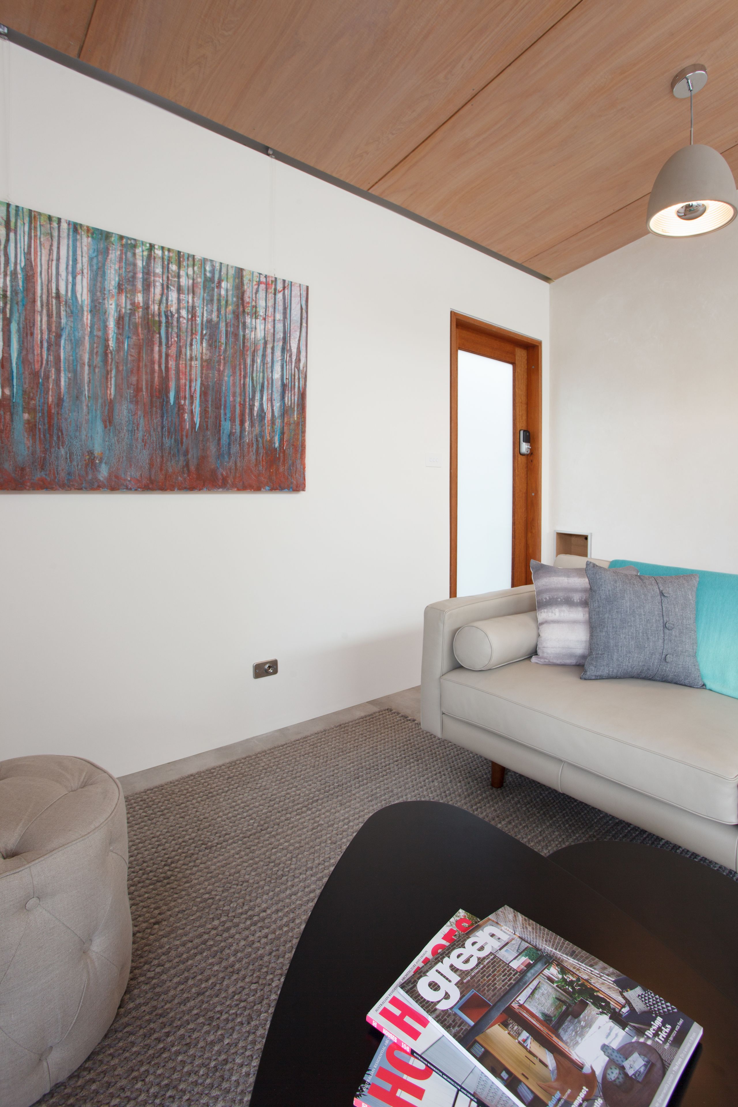 A modern living room with a sofa, a round coffee table, and a large abstract painting on the wall.