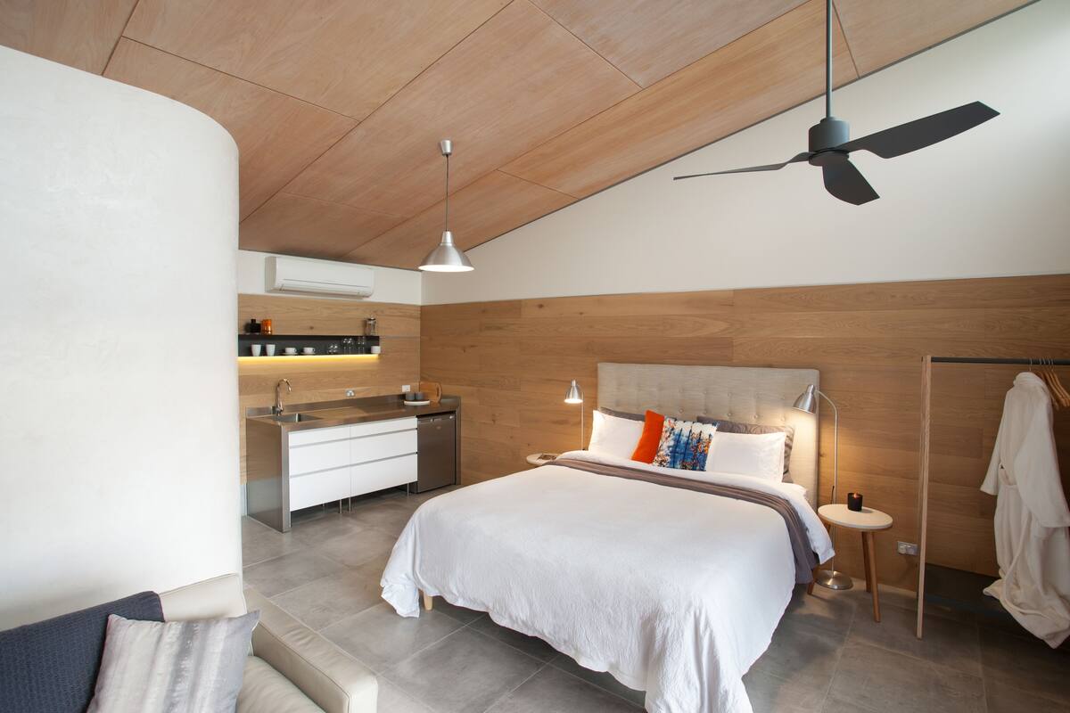 Un dormitorio moderno con cama, mesita de noche y ventilador de techo.