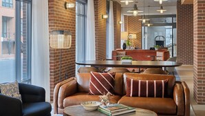 Eine moderne Lobby mit Ledersofas, einem runden Tisch und Pendelleuchten.