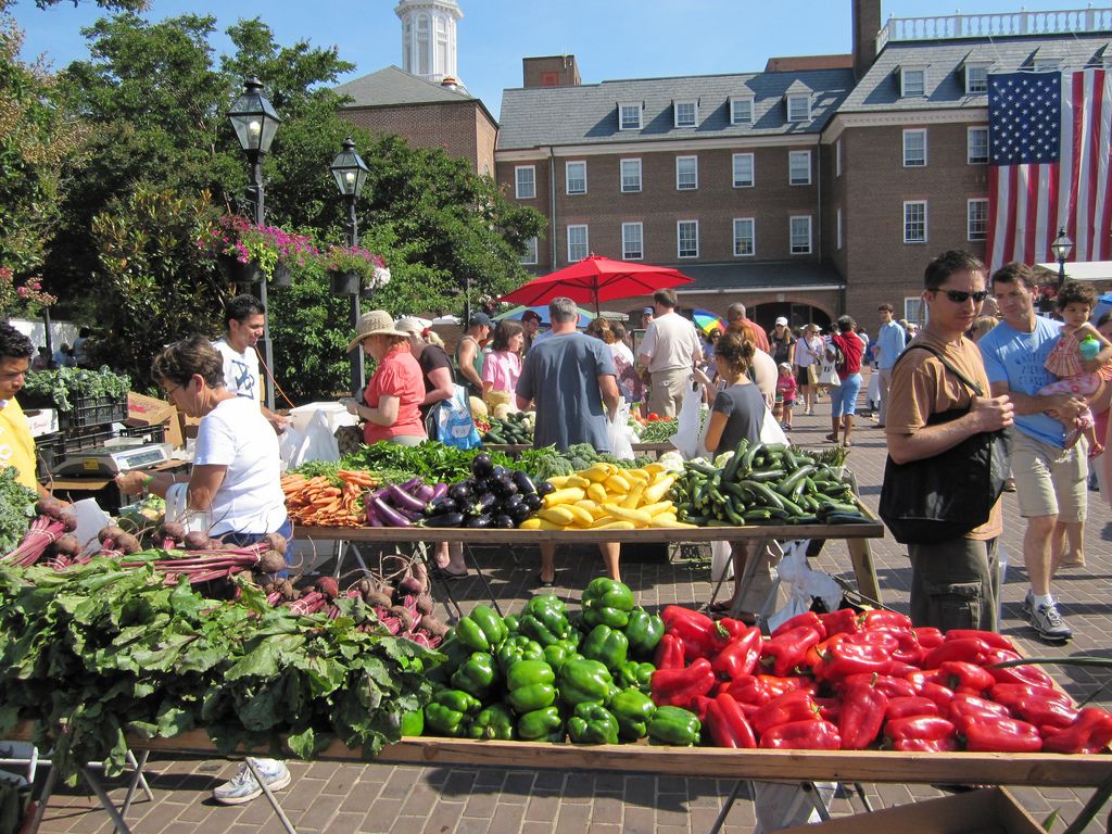 An outdoor market with various vegetables on display.