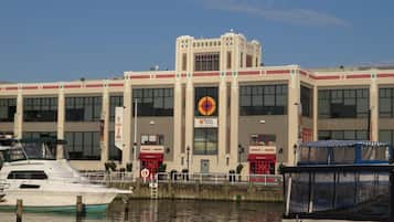 A building with a large circular logo, a dock with boats, and a clear sky.